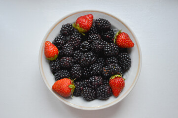 blackberries and strawberries on a plate on a white background