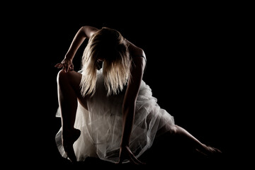 ballerina with a white dress and black top posing on black background. side lit silhouette. © Nikola Spasenoski