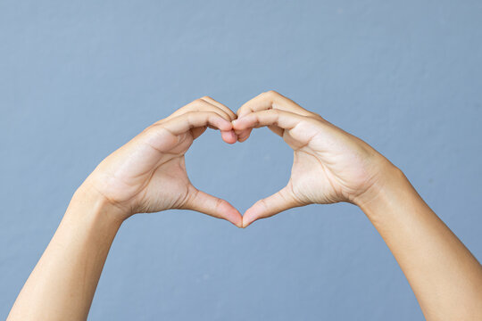 Man hands making sign Heart by fingers on grey background