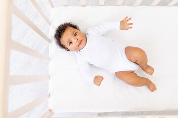 cute African American little baby in white bed for sleeping