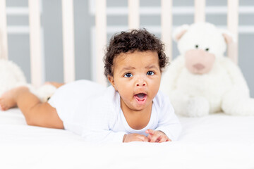 cute African-American little baby lying in bed for sleeping and yawning