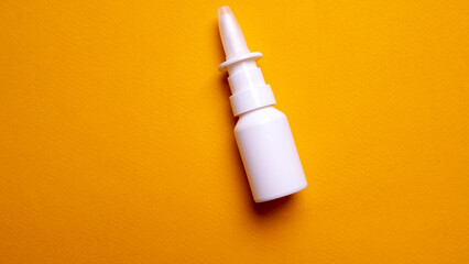 Bottle of nose drops on a yellow background close-up. Spray for the nose. View from above