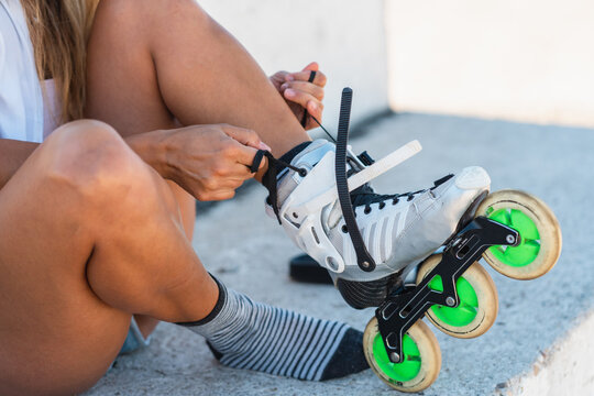 Anonymous woman putting on rollerblades in city