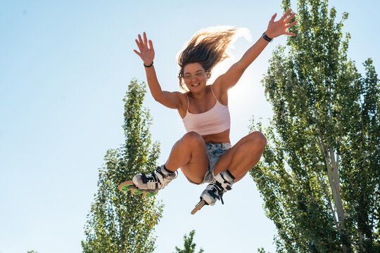 Energetic woman jumping in rollerblades in park