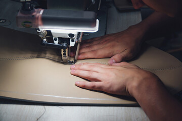 Working process of leather craftsman. Tanner sews leather on a special sewing machine, close up.