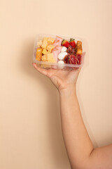 Hand holding lunch box with cheese, ham, bacon, salami and eggs. Set of gourmet snacks.