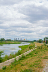 Fototapeta na wymiar river and blue sky with clouds and green field