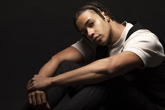 Young man with braids in dark studio