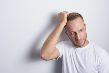 Thoughtful man touching his hair in a white background looking outside