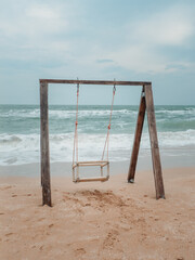 Wooden swing on the shores of the raging sea.