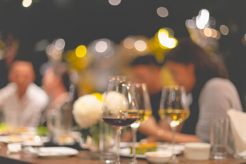 Glasses for wine and people at dinner table with blurred background and warm lights. elebrating evening concept. indoor