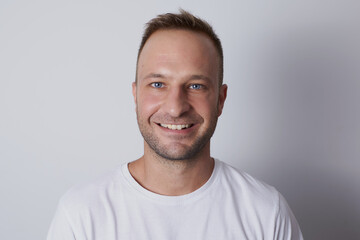 Man smiling in a white background with white t-shirt