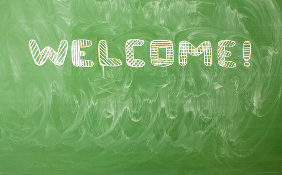 English lettering - welcome written in white chalk on a green chalkboard and copy space.  Concept - offline education