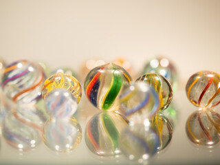 Glass marbles handmade antique with colourful swirl patterns on a reflective glass surface