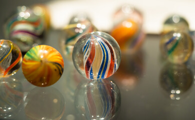 Glass marbles handmade antique with colourful swirl patterns on a reflective glass surface