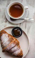 croissant with jam and tea on a white wooden background. background texture screensaver. photo with...