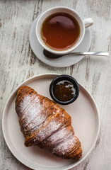 croissant with jam and tea on a white wooden background. background texture screensaver. photo with space for caption