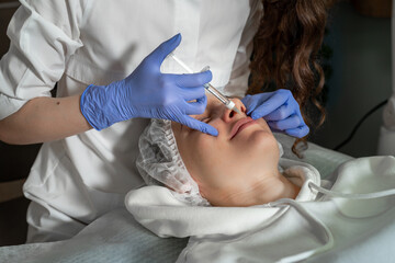 A doctor cosmetologist performs a lip contouring procedure for a young woman in a beauty parlor...