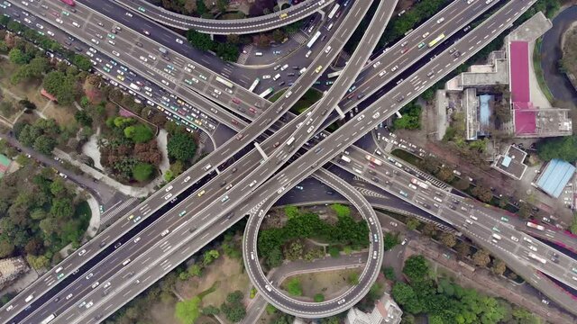 Time lapse of traffic on large interchange at Shanghai city, aerial top-down view. Stacked roads and flyovers, fast car movement on lanes, slower traffic on streets and roundabout on ground level