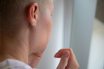 Attractive young adult woman apply facial cream look in mirror, beautiful healthy lady wrapped in...