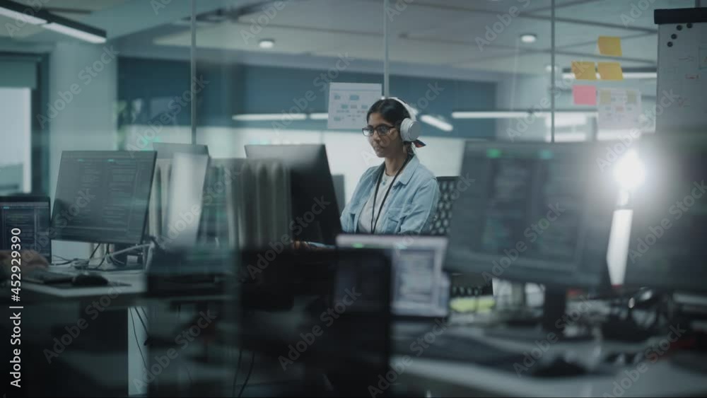 Poster Diverse Office: Indian IT Programmer Working on Computer. Female Specialist Creating Innovative Software. Engineer Developing App, Program, Video Game. Wearing Headphones Listening Podcast, Music