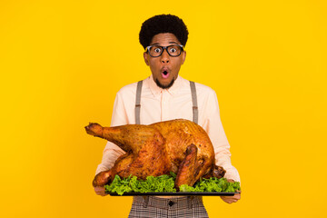 Photo portrait man in glasses keeping baked chicken on thanksgiving day amazed isolated vivid...