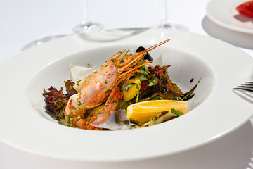 Fresh healthy salad with shrimp, mussels, rucola, lettuce and vegetables. Elegant contemporary appetizers with seafood on white table with wine glass. Still life - Lunch in seafood restaurant.