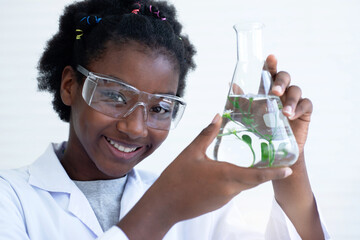 Dark-skinned student holding test tube  and looking at camera, learning about plant biology in laboratories, selective focus