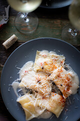 ravioli pasta with sauce in a plate on a dark background with wine