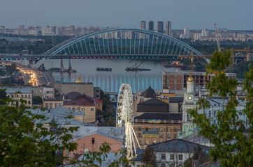 Evening view of the Podilskyi Bridge, the Dnieper River and the Ferris Wheel at Kontraktova Square, Kyiv, Ukraine.