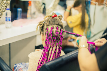 Girl in a barber shop makes her pink afro-pigtails