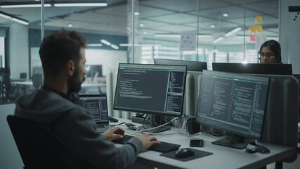 Diverse Office: IT Programmer Working on Desktop Computer. Male Specialist Creating Innovative Software Engineer Developing App, Program, Video Game. Terminal with Coding Language. Over Shoulder