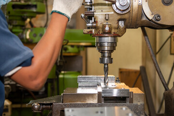 The machine operator drilling the hole on metal plate with NC milling machine. The shop floor...