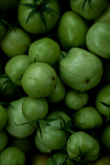 reen tomato (unripe) in wicker basket on wooden background. Unripe green tomato in bowl for fried dish or salted pickled vegetables. Raw green tomato on table for dinner