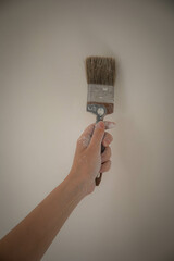 a woman's hand with a paintbrush smeared with paint. a woman paints the walls with white paint. hand smeared in white paint work wall painter paintbrush