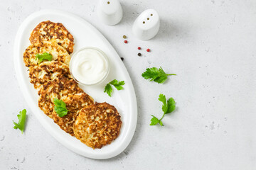 Broccoli chicken fritters on white dish with sour cream sauce. Top view, space for text.