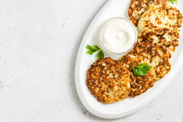 Courgette corn  fritters on white dish with sour cream sauce. Top view, space for text.