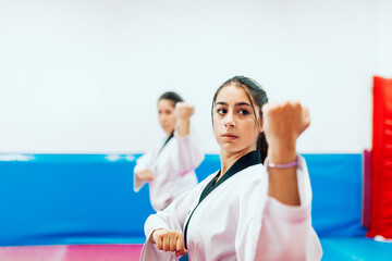 Two young women practice taekwondo in a training center