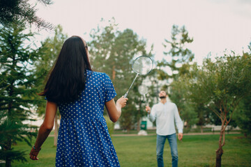 Young adult couple playing badminton in the park.