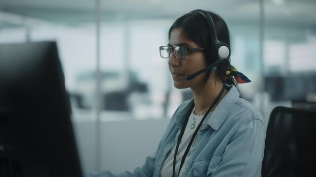 Call Center Office: Portrait of Friendy Indian Female IT Customer Support Specialist Working on Computer. Business Entrepreneur Using Headset to Talk with Client via Online Video Conference Call