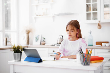 Homeschooled little young girl student having online class using digital tablet