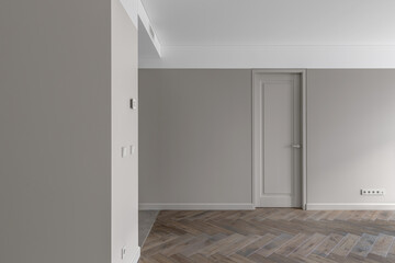 Simple Modern Beige-Grey Wall with grey light switch and grey socket in the Empty Room with open door and oak wood floor. Interior Design Element of contemporary interior design at modern house