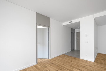 Empty minimalist modern room with white walls, opened grey door, grey floor tiles and oak wood floor