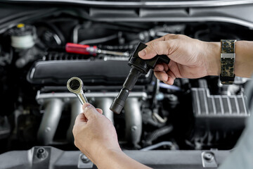 Close up spark plug coil in hand a man and use block wrench remove a bolt in service in garage and...