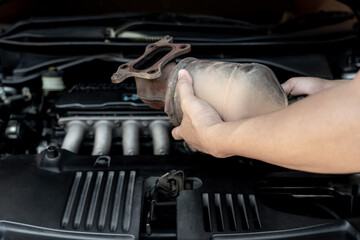 Close up old catalytic converter in hand Technician remove from engine gasoline car dust clogged...