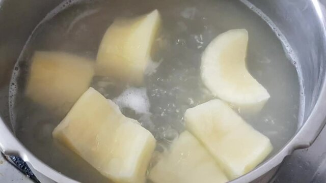 Boiling tapioca cut pieces in a pressure cooker. Closeup