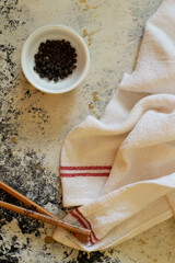 Chopsticks, towel and a small bowl full of black pepper