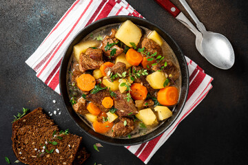 Traditional Irish stew in a black bowl on a dark background. Stew of lamb, potatoes, onions,...