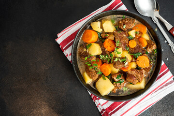 Traditional Irish stew in a black bowl on a dark background. Stew of lamb, potatoes, onions, carrots, and thyme. Traditional dish of St. Patrick's Day.
