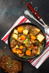 Traditional Irish stew in a black bowl on a dark background. Stew of lamb, potatoes, onions, carrots, and thyme. Traditional dish of St. Patrick's Day.